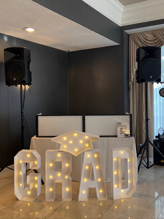 DJ: Setup, Decorative LED letters spelling 'GRAD' in a room with a desk and speakers.