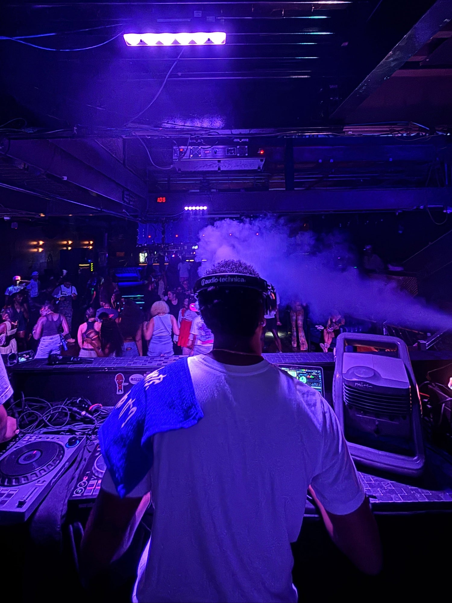 DJ_3o7 at a music event with purple lighting and equipment